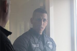 Man in uniform speaking to another person.