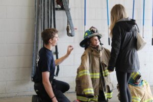 Child dressed in firefighter gear smiling