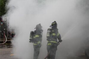 Firefighters battling heavy smoke with hose
